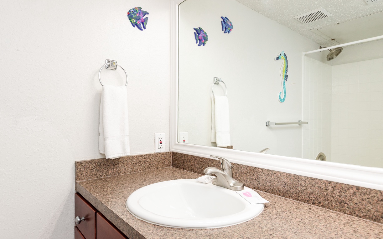 Refresh in your private bathroom featuring granite countertops, tropical fish wall art, and plush towels ready for your stay.