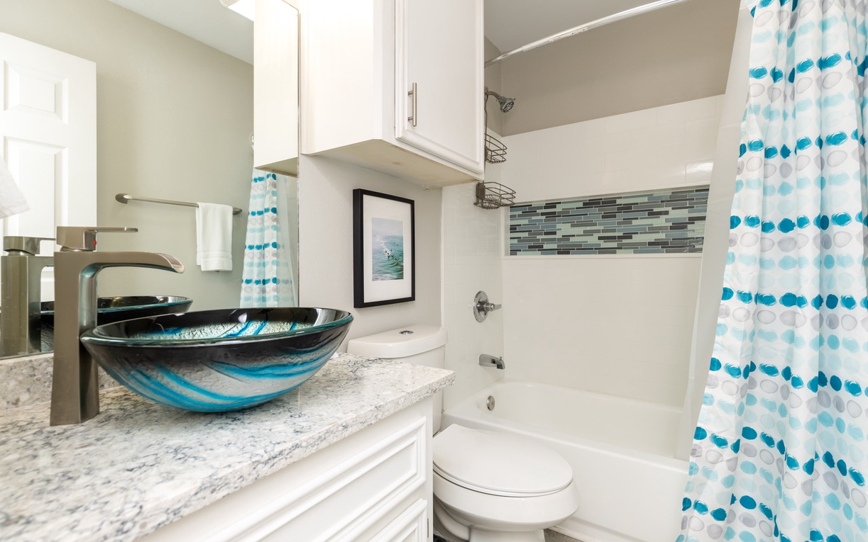 Refresh yourself in this beautifully appointed bathroom with artistic glass vessel sink, granite counters, and sparkling tub-shower combo.