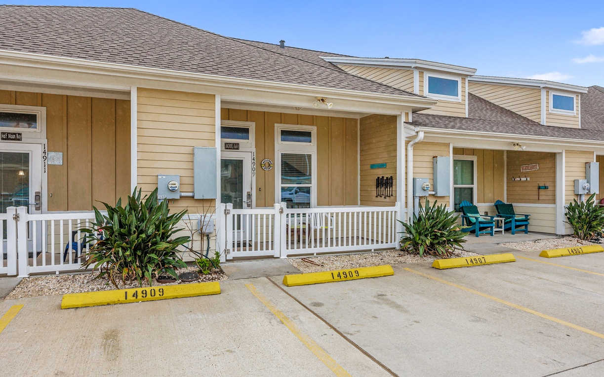 Charming beachside cottages with covered porches and designated parking spaces create a welcoming coastal retreat atmosphere.