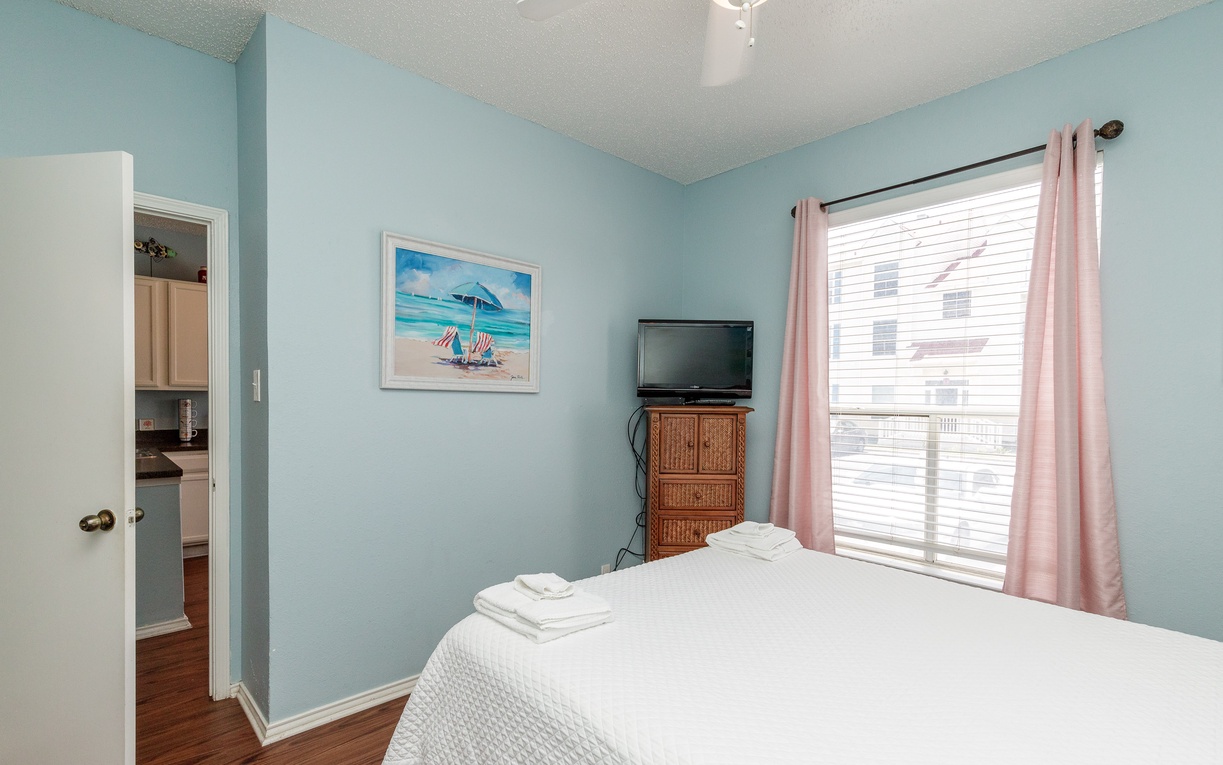 Unwind in your serene bedroom with coastal charm, soft blue walls, and natural light streaming through your private window.