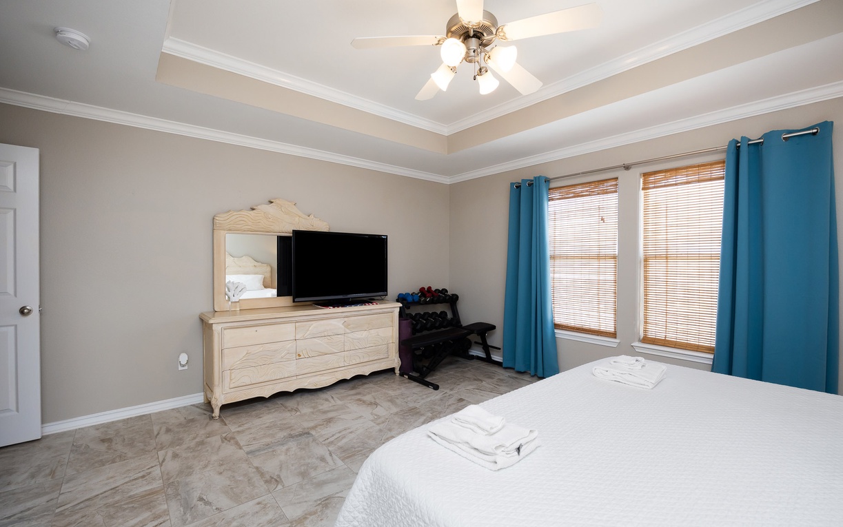 Rest peacefully in your spacious bedroom with ceiling fan, flat-screen TV, and beautiful natural light streaming through windows.