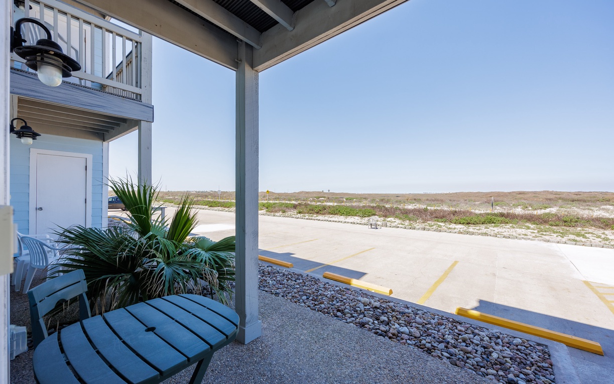 Ground-floor patio features outdoor seating and natural landscaping, with convenient parking and coastal views nearby.