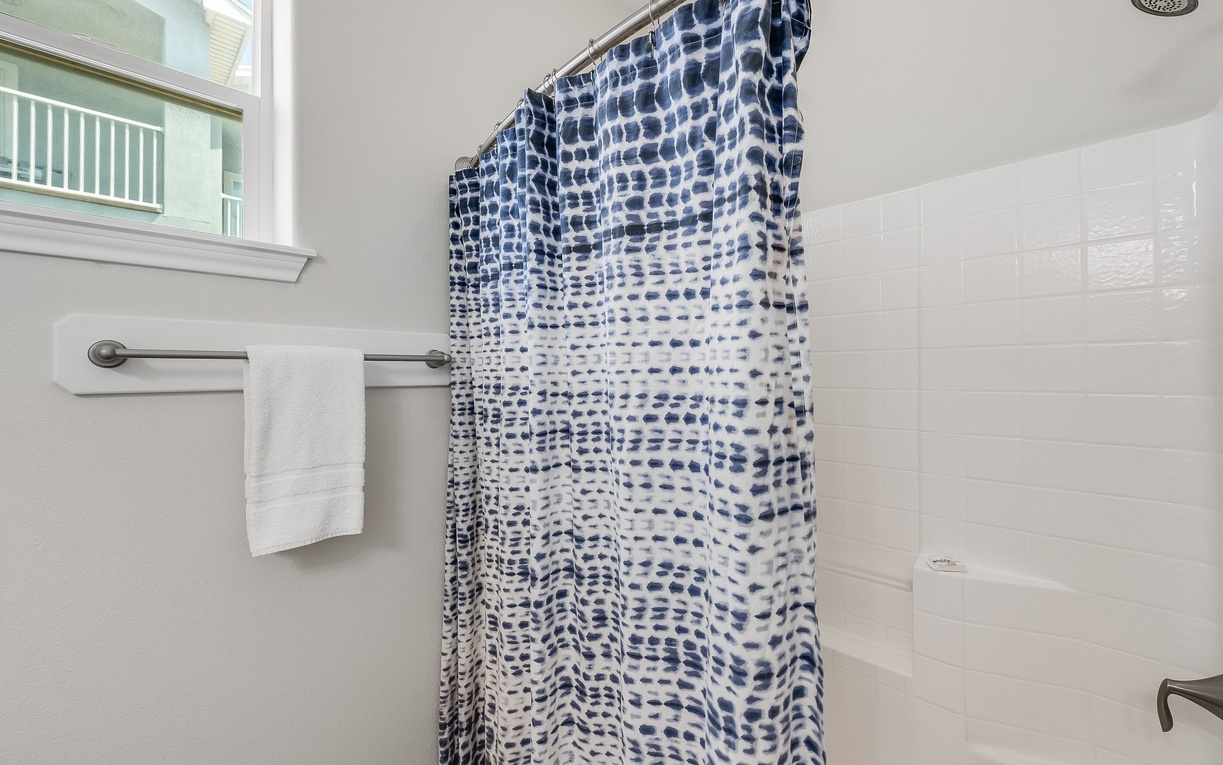 Step into your spa-like shower with soothing blue wave-patterned curtain and pristine white subway tiles for your morning refresh.
