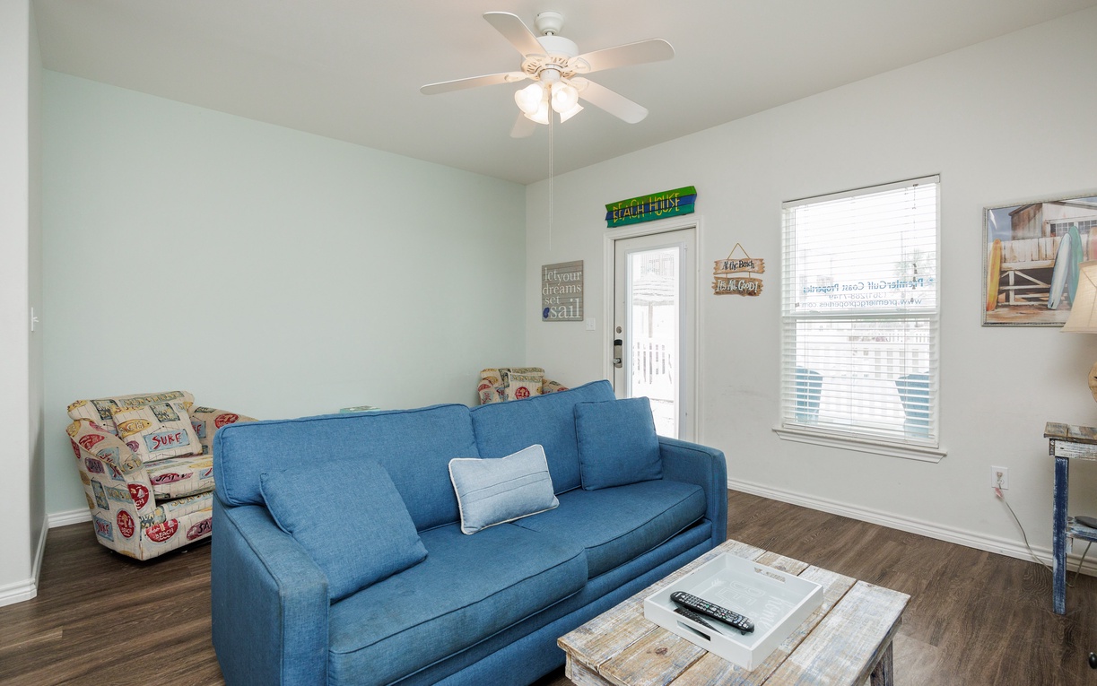 Sink into this comfortable blue sofa while your ceiling fan keeps you cool and natural light streams through large windows.