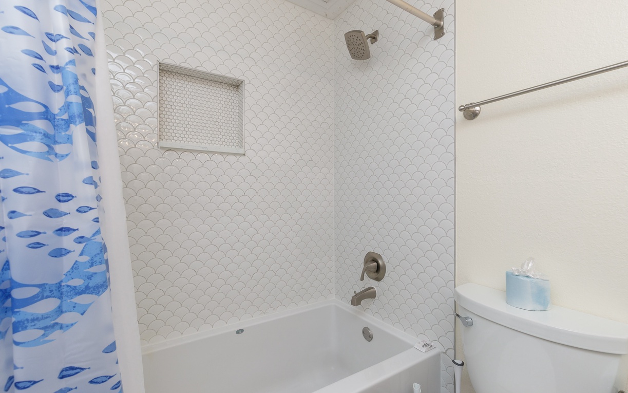 Unwind in your stylish bathroom featuring a deep soaking tub, elegant fish-scale tiling, and coastal-themed touches.