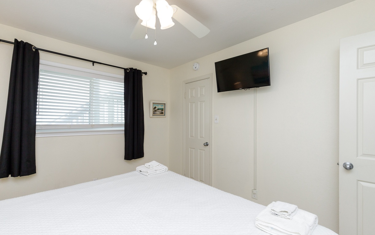 Relax in your bright, comfortable bedroom with a king size bed, crisp linens, blackout curtains for restful sleep, and convenient wall-mounted TV for unwinding.