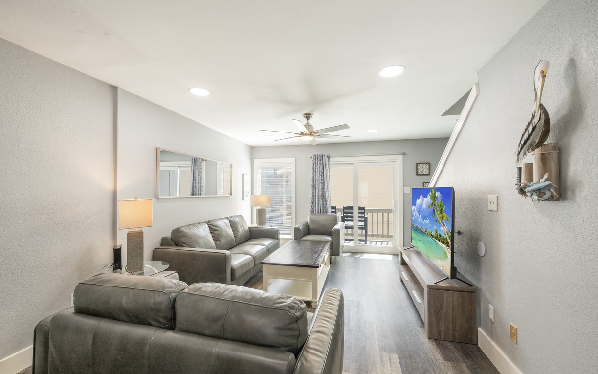 Relax in your spacious living room with plush leather seating, queen size sleeper sofa, modern entertainment center, and balcony access.