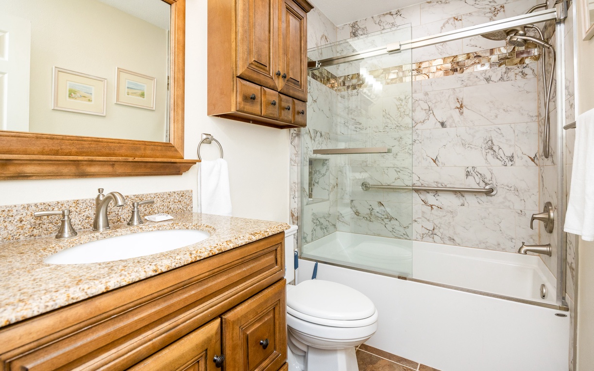Unwind in your private bathroom featuring elegant marble shower, granite vanity, and warm wood finishes for a spa-like retreat.