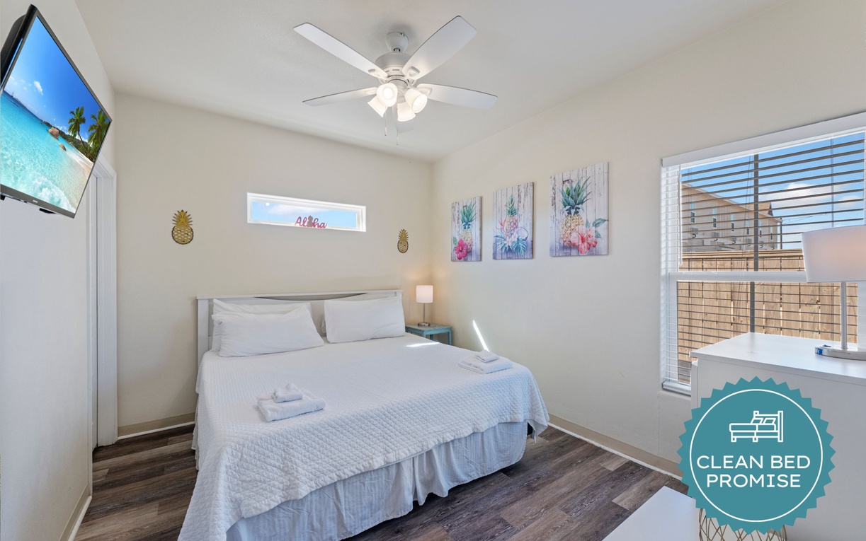 Sink into comfort in this bright bedroom with fresh linens, tropical artwork, and your own ceiling fan for perfect temperature control.