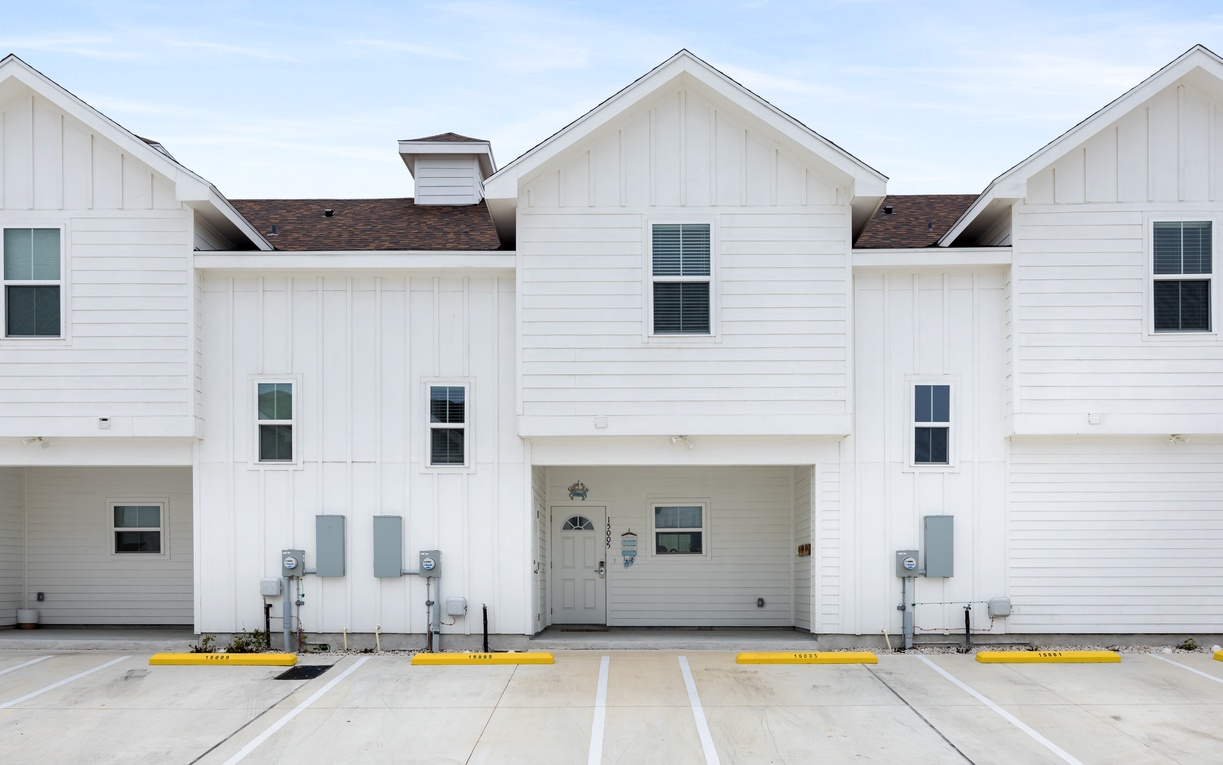 Modern townhouse complex featuring clean white architecture with organized parking spaces and convenient front door access.