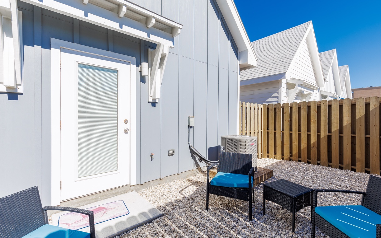 Your private patio offers comfortable seating with blue cushions where you can unwind under the bright sky.