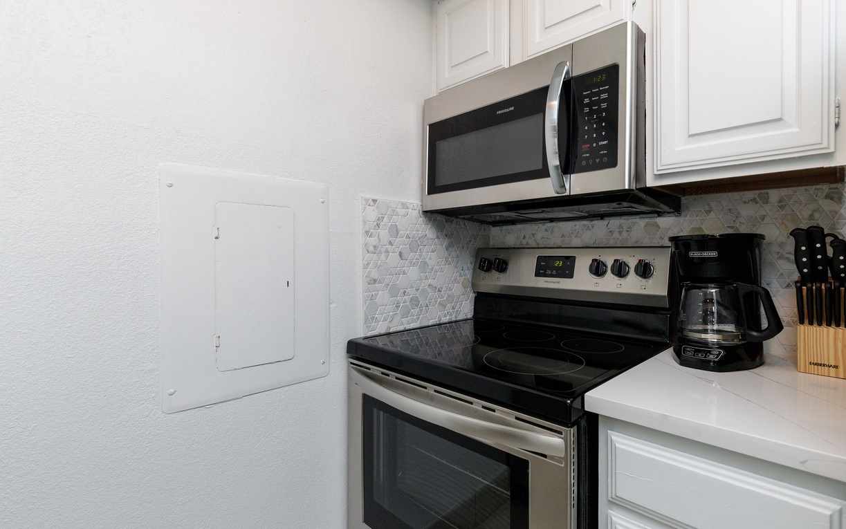Your fully equipped kitchen features modern stainless steel appliances, including microwave, oven, and coffee maker - perfect for preparing meals during your stay.