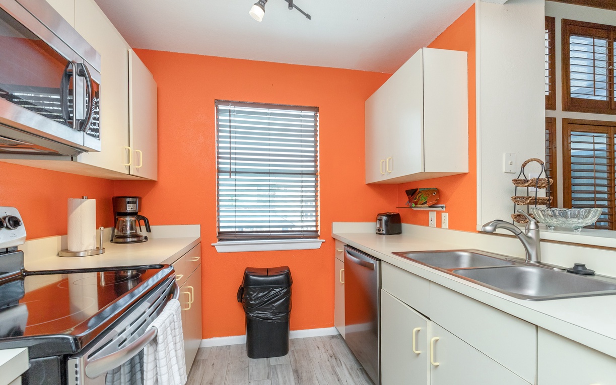 Cook your favorite meals in this vibrant kitchen, complete with modern appliances and cheerful orange walls that make every cooking session feel energizing.