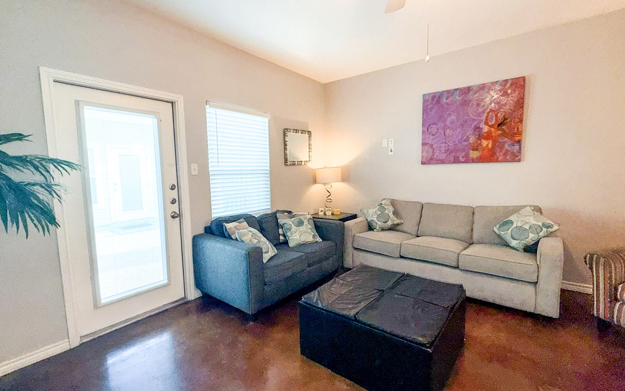 Sink into your spacious living room with plush seating, warm lighting, and vibrant artwork creating the perfect atmosphere for relaxation.