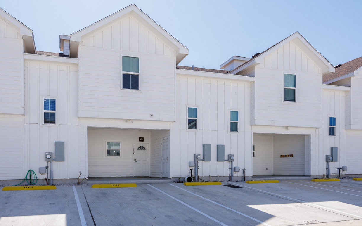 Modern white townhomes with attached garages offer convenient parking and a fresh, contemporary design in a well-maintained development.