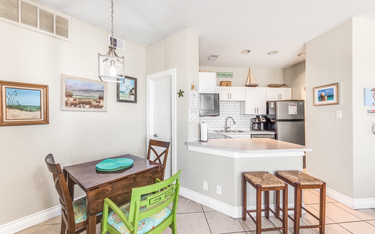 Your open-concept kitchen and dining space features modern appliances, coastal artwork, and cheerful seating perfect for morning coffee or casual meals.