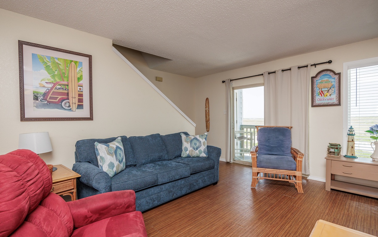 Relax in your comfortable living room with plush sofas and coastal artwork creating the perfect space to unwind after beach adventures.