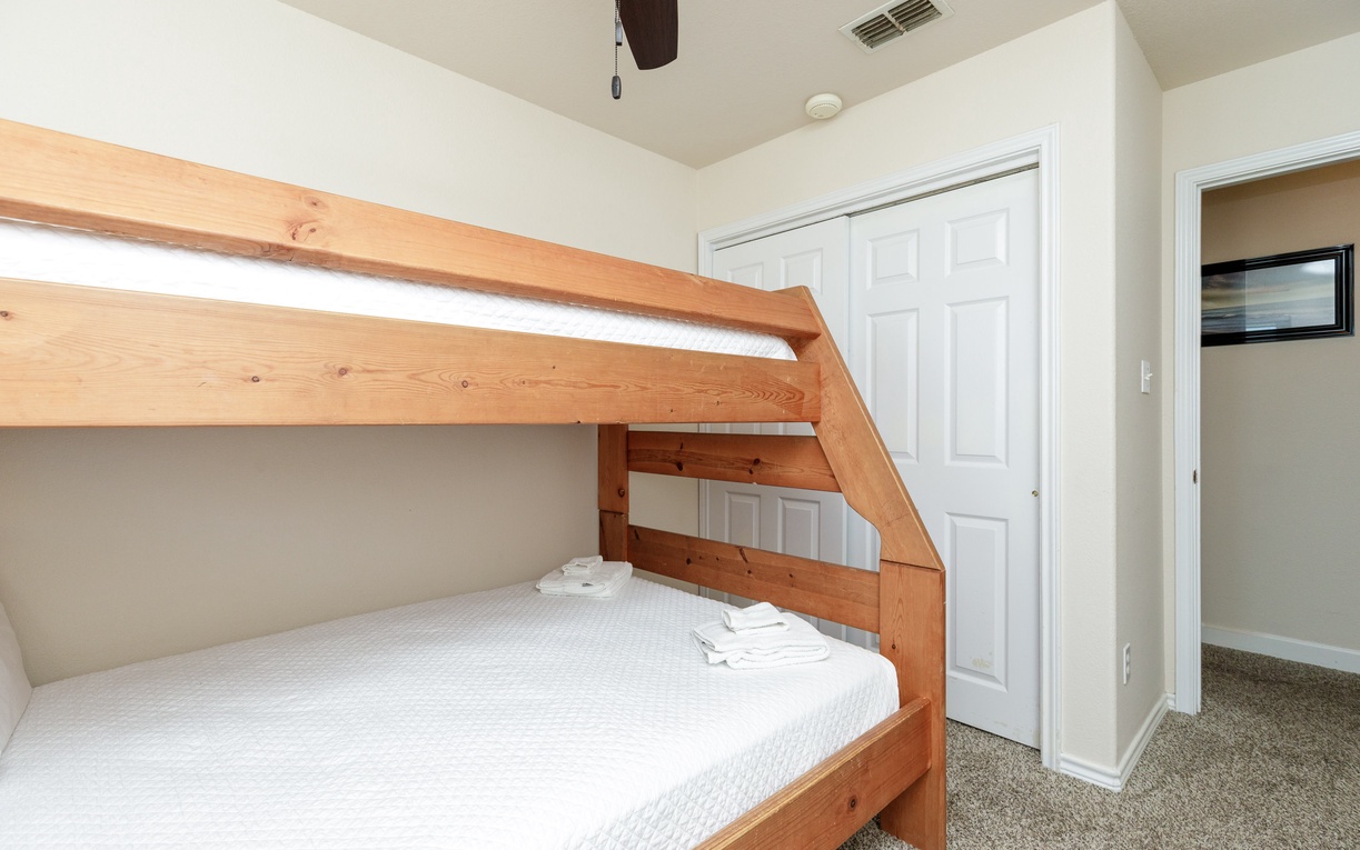 Your kids will love this cozy bunk bed setup with fresh linens, plenty of storage, and a ceiling fan for comfort.