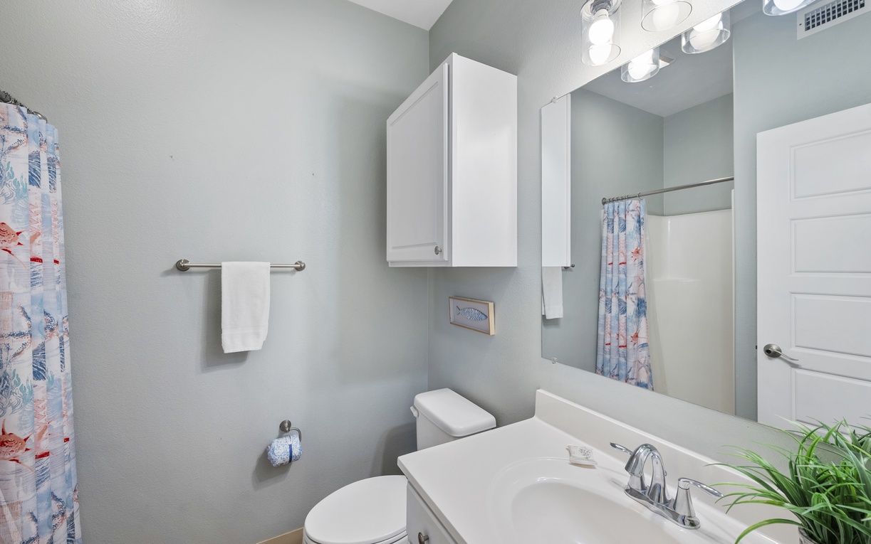 Your private bathroom features bright vanity lighting, ample storage, and cheerful coastal-themed touches that make your morning routine feel like a spa retreat.