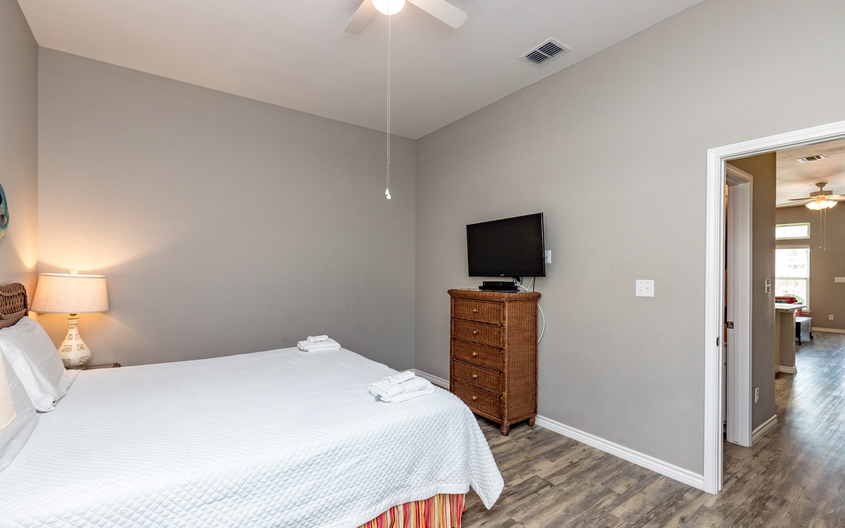 Unwind in your peaceful bedroom with soft gray walls, crisp linens, and a flat-screen TV for cozy evenings.