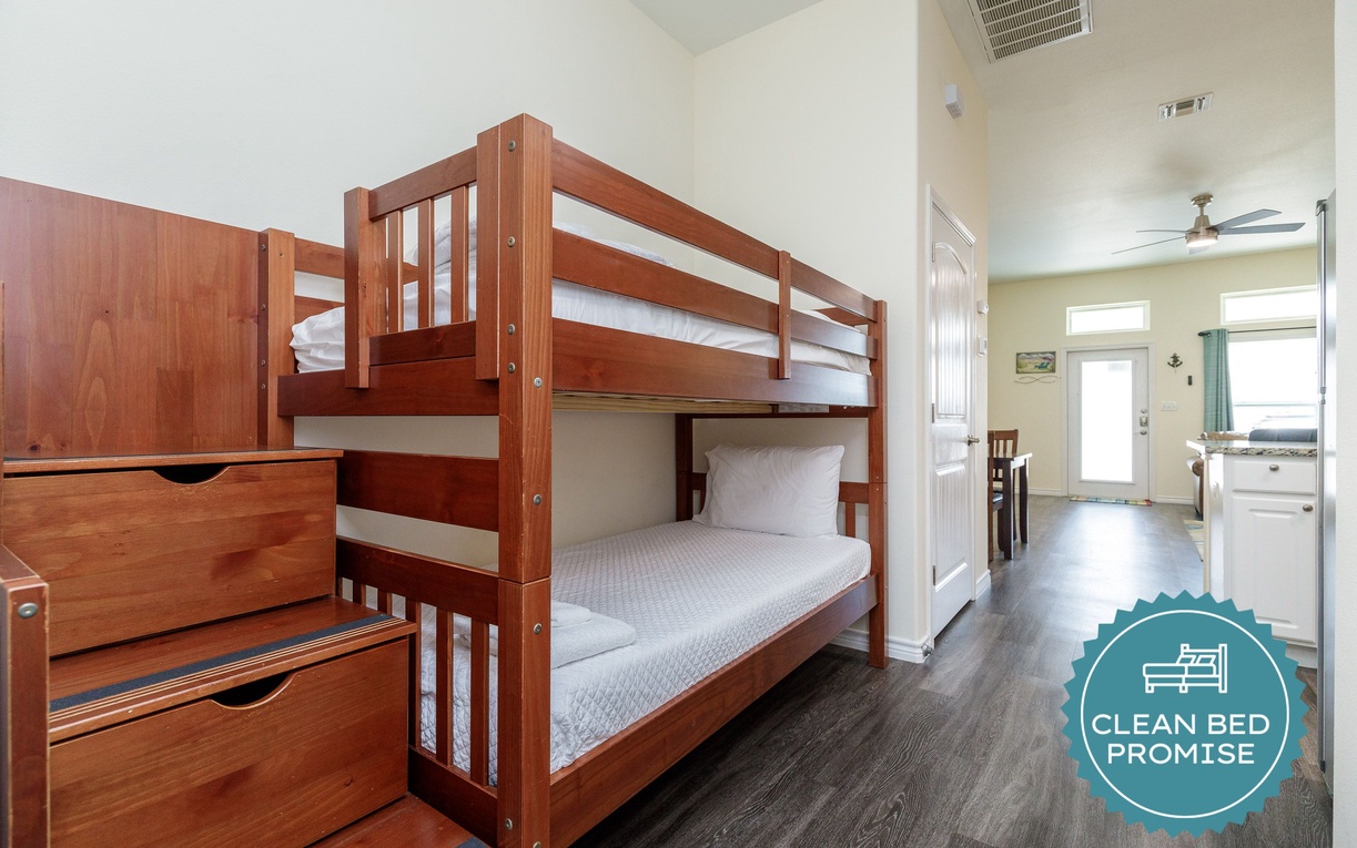 Your cozy bunk bed setup offers comfort and convenience, with built-in storage steps and fresh linens in this bright, welcoming space.