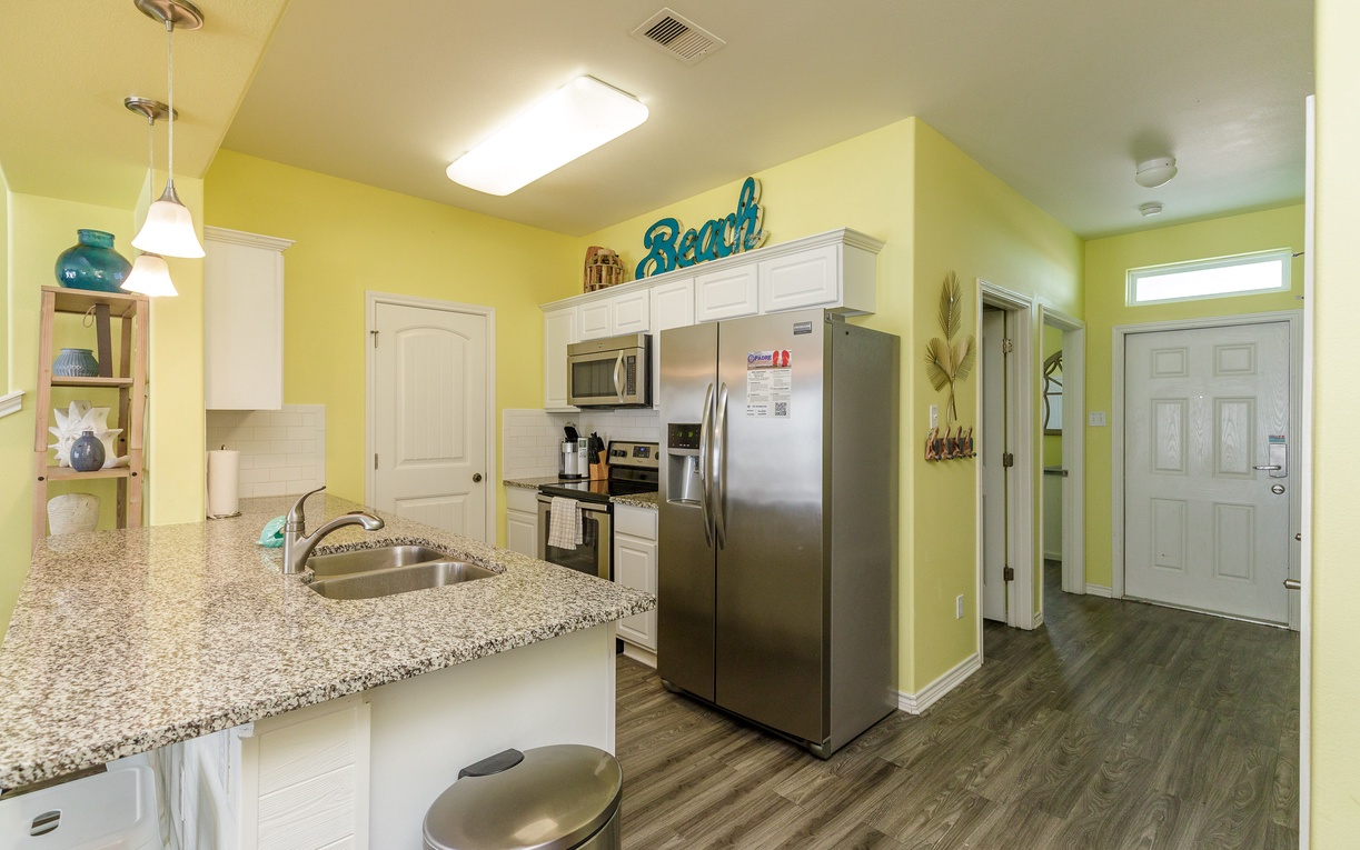 Your bright, fully-equipped kitchen awaits with granite countertops, stainless appliances, and cheerful yellow walls that make meal prep feel like vacation.