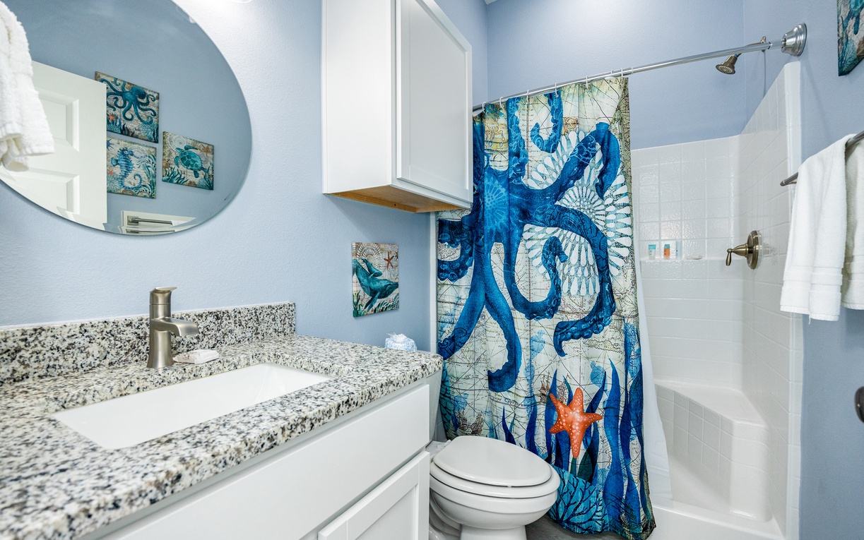 Refresh in your ocean-themed bathroom with granite countertops, whimsical blue octopus décor, and pristine white fixtures creating a coastal retreat.