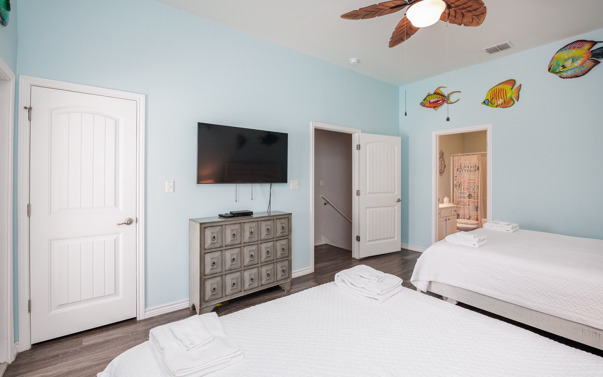 Your tropical-themed bedroom features twin beds, entertainment, and an ensuite bathroom with playful fish decor.