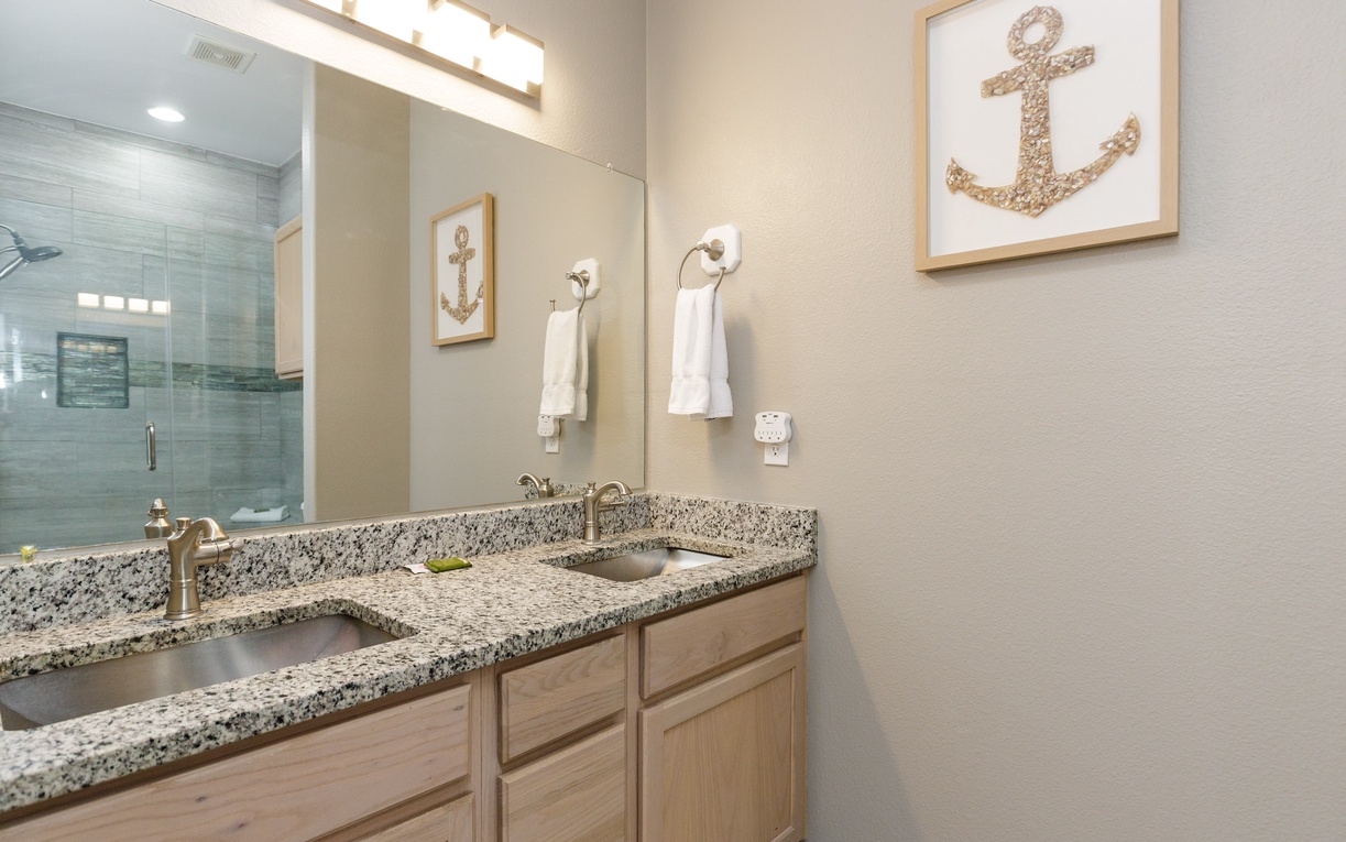 Your stylish bathroom features granite counters, coastal decor, and a glass shower—perfect for refreshing after beach days.
