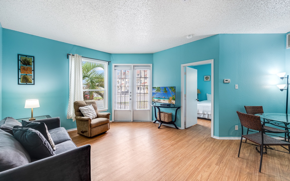 Relax in your bright, cheerful living space with tropical turquoise walls, comfortable seating, and glimpses of your private bedroom.