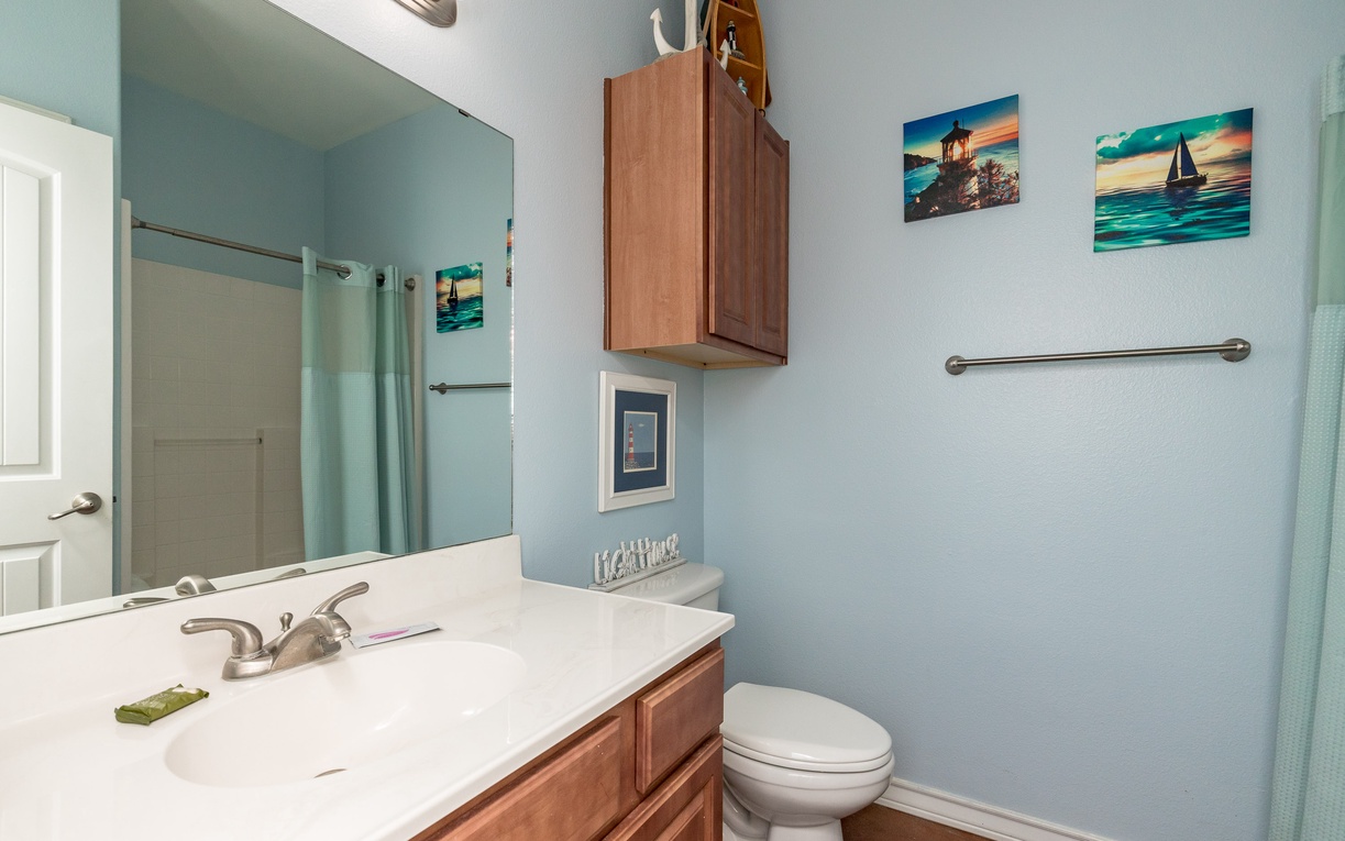 Your serene coastal-themed bathroom features soothing blue tones, warm wood vanity, and nautical artwork creating a spa-like retreat.