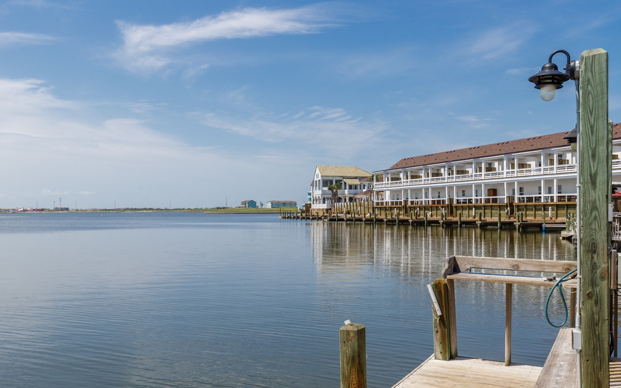 Waterfront property with private dock access on calm bay waters, featuring charming multi-story buildings and peaceful marina setting.
