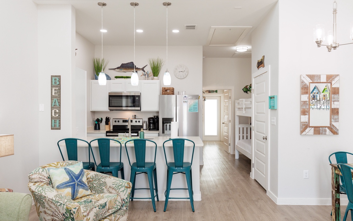 Enjoy your morning coffee at this bright kitchen island while the coastal decor and turquoise accents create a relaxing beach house atmosphere.