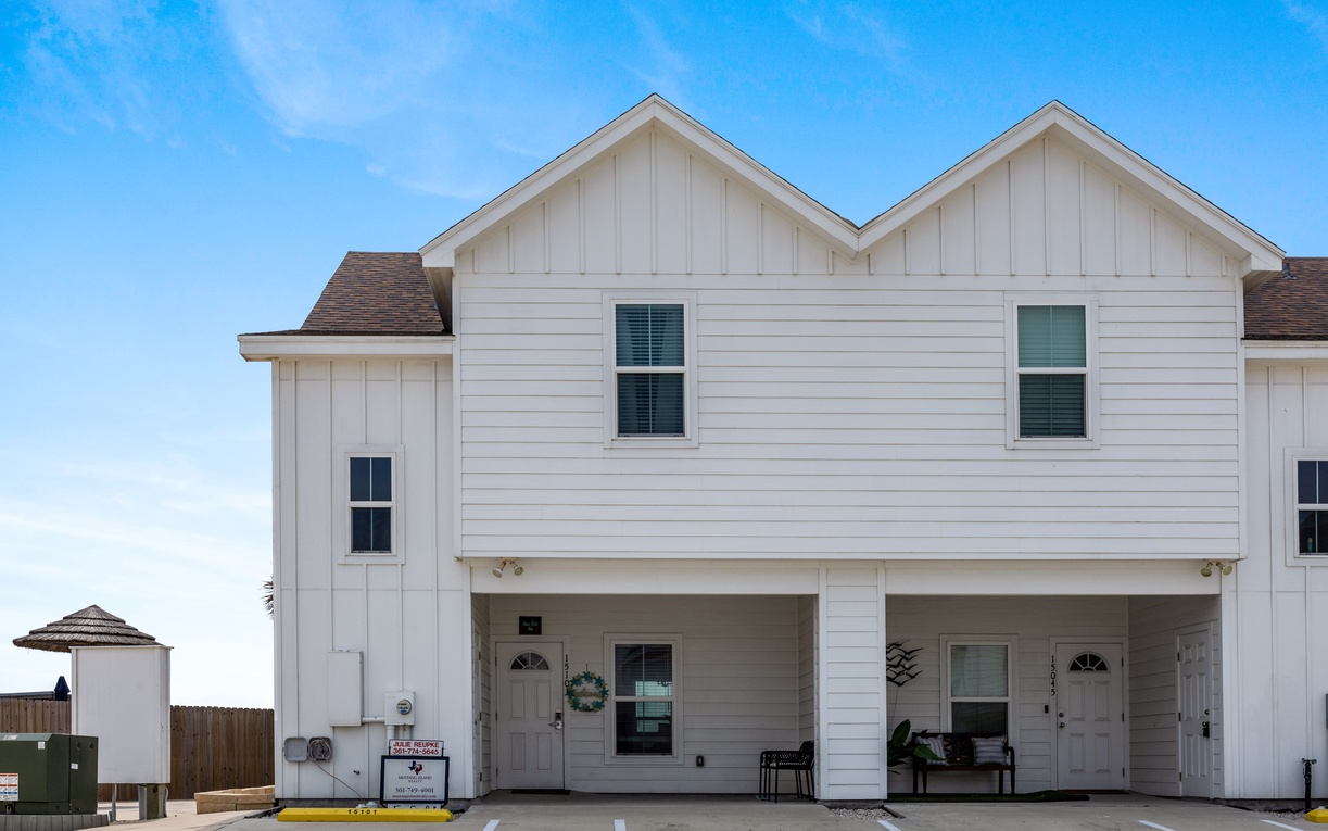 Modern duplex with covered parking and welcoming front porches under bright blue skies.