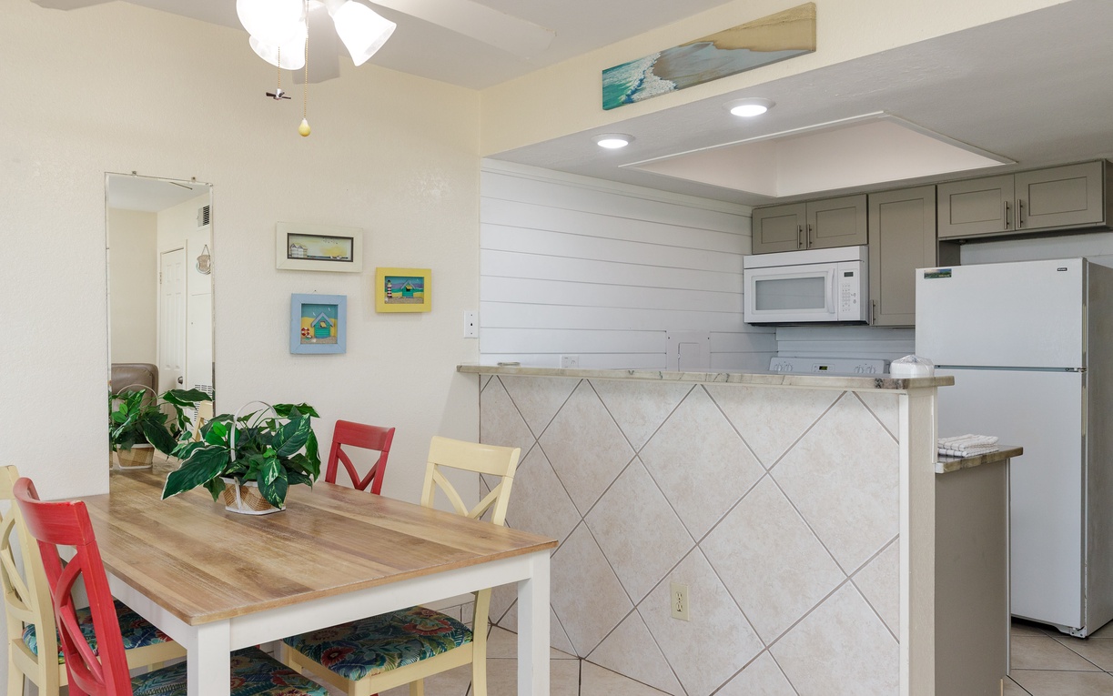 Enjoy relaxed meals at your charming dining table, perfectly positioned next to your fully equipped kitchen with modern appliances and coastal artwork.