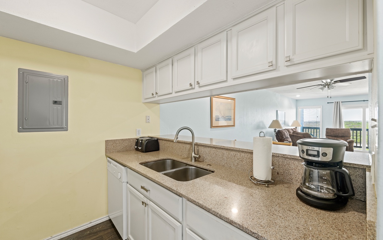 Your fully equipped kitchen opens to a bright living space with coastal views, ready for morning coffee or preparing beachside meals together.