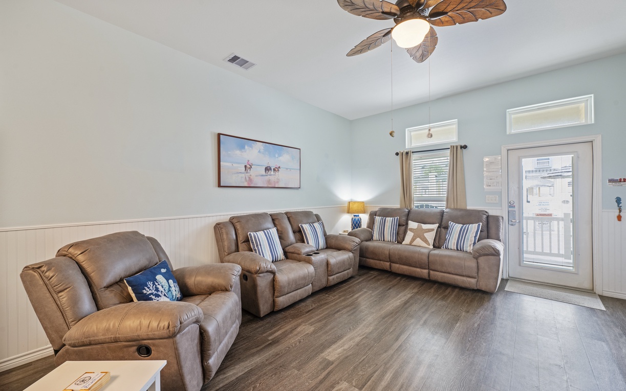 Relax in your spacious living room with plush leather recliners and coastal charm, complete with tropical ceiling fan for ultimate comfort.