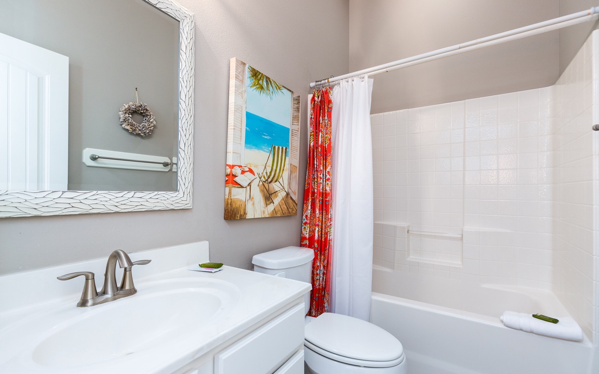 Step into your private bathroom featuring a spacious tub-shower combo, stylish vanity, and cheerful beach-themed decor that brings vacation vibes to your daily routine.