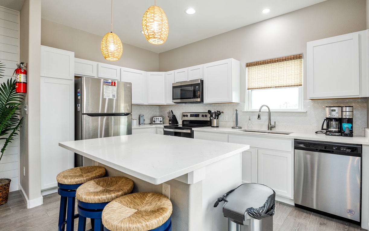 Your modern kitchen awaits with gleaming appliances, warm pendant lights, and a breakfast bar perfect for morning coffee or evening conversations.