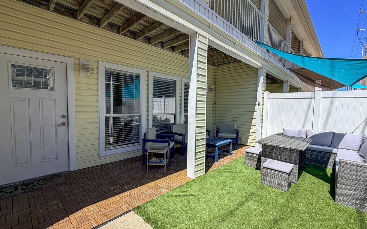 Your private patio retreat features comfortable wicker seating with plush cushions and colorful Adirondack chairs, perfect for morning coffee or evening relaxation.