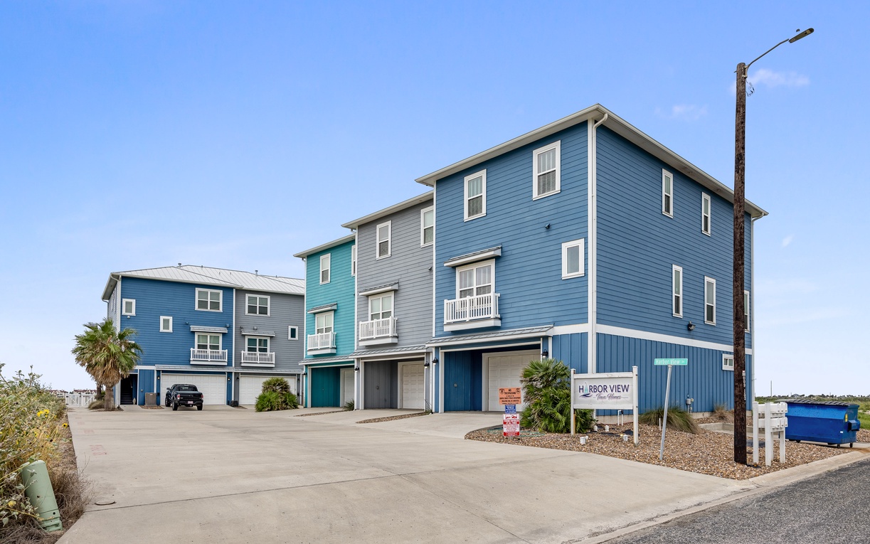 Charming coastal rental complex featuring bright blue buildings with modern amenities and convenient parking for your beach getaway.