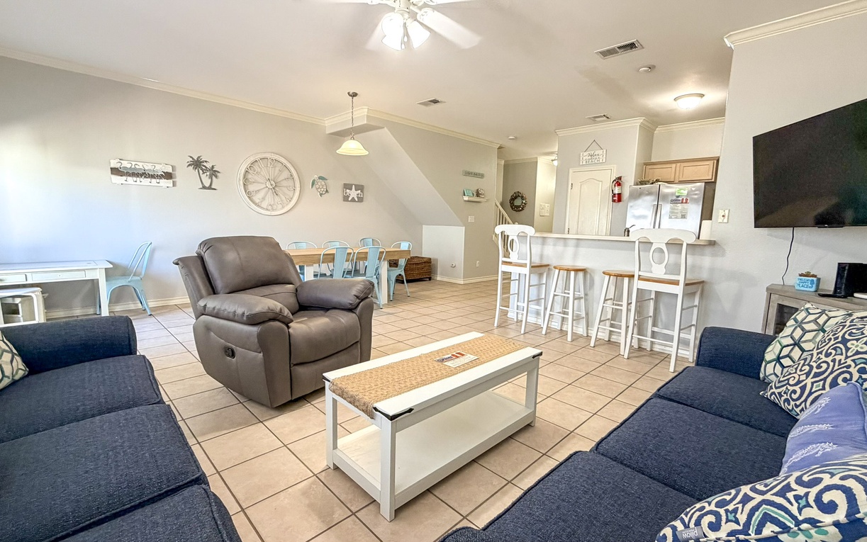 Sink into coastal comfort in your open-concept living space, where beach-themed decor and cozy seating create the perfect vacation retreat.