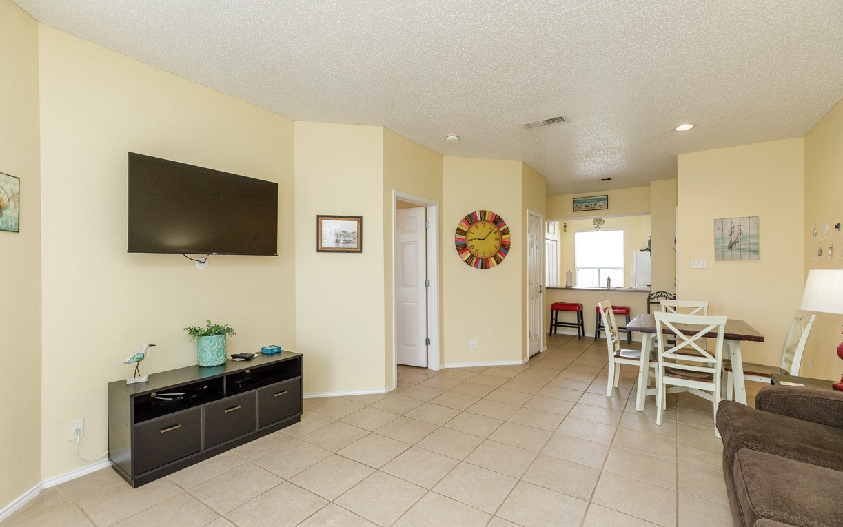 Relax in your bright, open living space with comfortable seating, wall-mounted TV, and cozy dining area perfect for family meals.