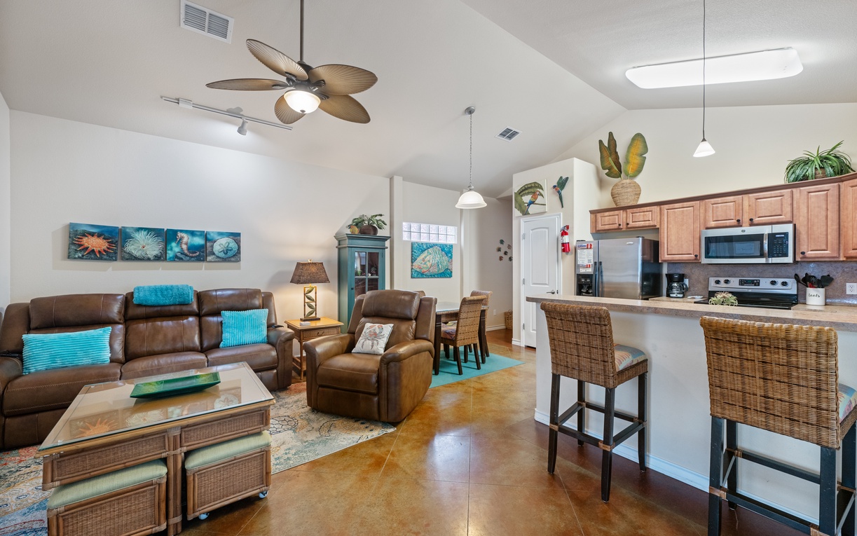 Relax in your bright, open-concept living space featuring comfortable leather seating and a fully equipped kitchen for memorable meals together.