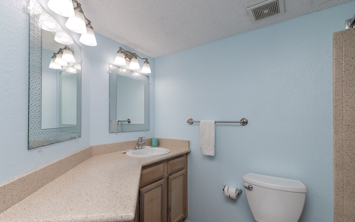 Refresh in your spacious bathroom with dual vanities, decorative mirrors, and soothing blue walls that create a spa-like retreat.