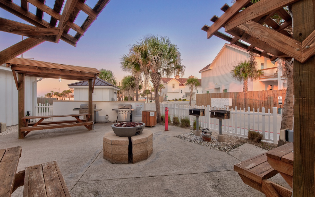 Enjoy the community outdoor paradise featuring a fire pit, BBQ area, and dining space under wooden pergolas—perfect for sunset gatherings.