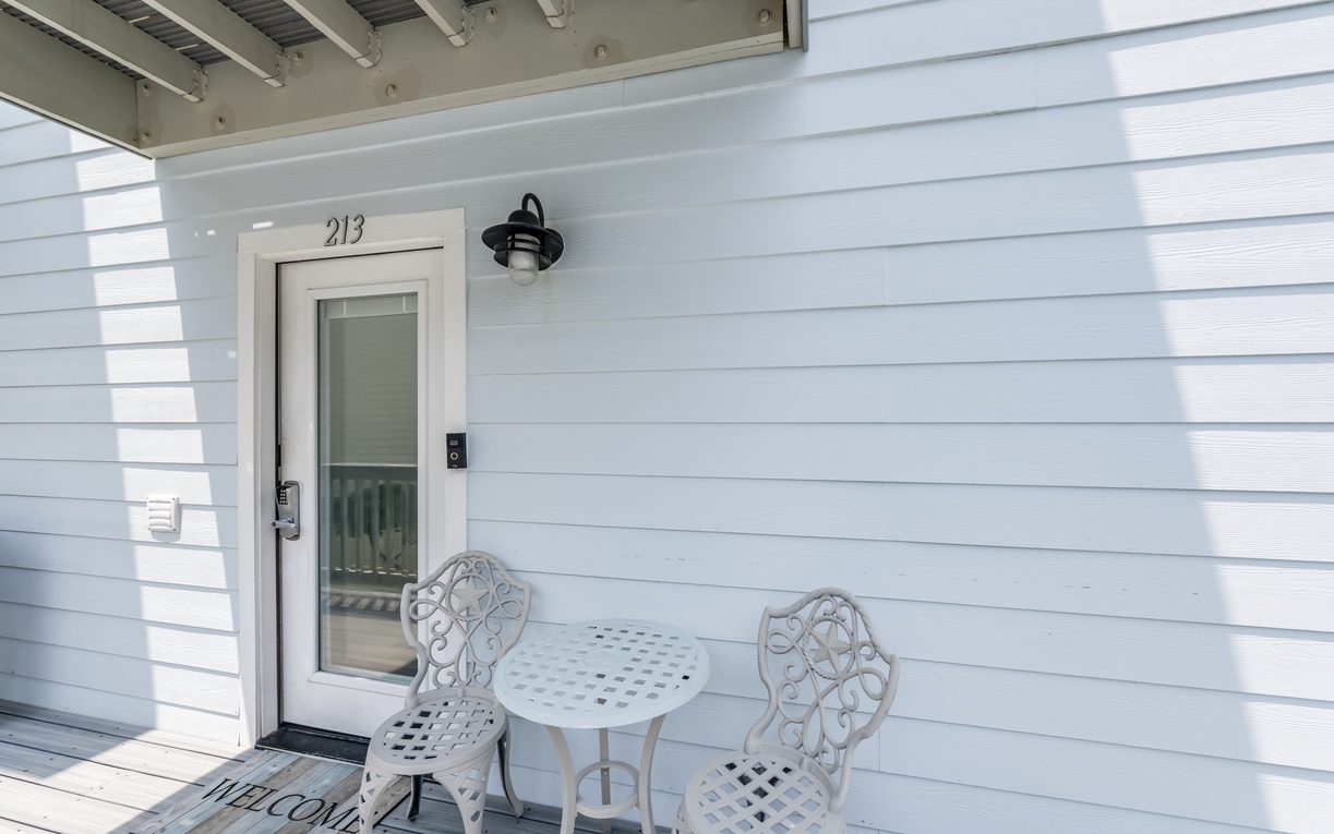 A charming entrance to unit 213 features a cozy bistro set where you can enjoy your morning coffee or unwind with evening drinks in the fresh air.