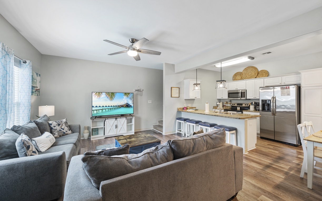 Sink into plush sofas in your open-concept living space, where coastal vibes meet modern comfort with a fully-equipped kitchen perfect for family gatherings.