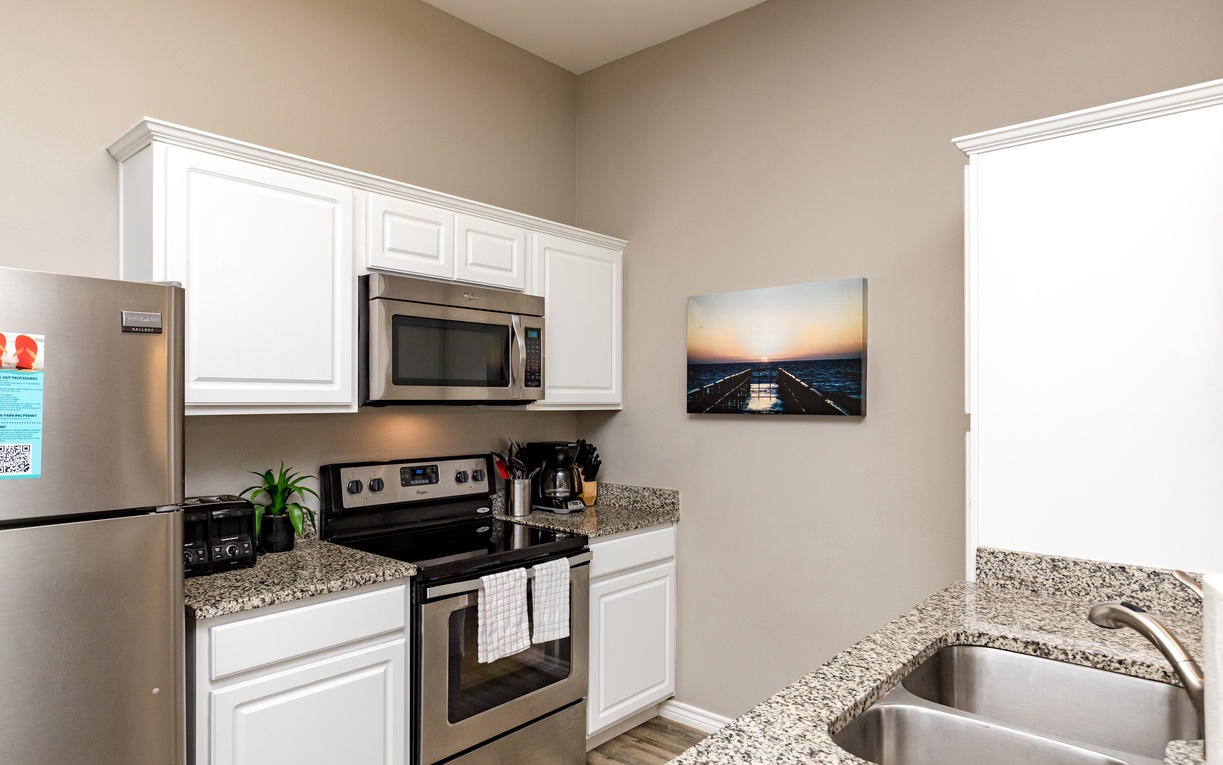 Cook your favorite meals in this bright, fully equipped kitchen featuring granite countertops, stainless appliances, and crisp white cabinetry.