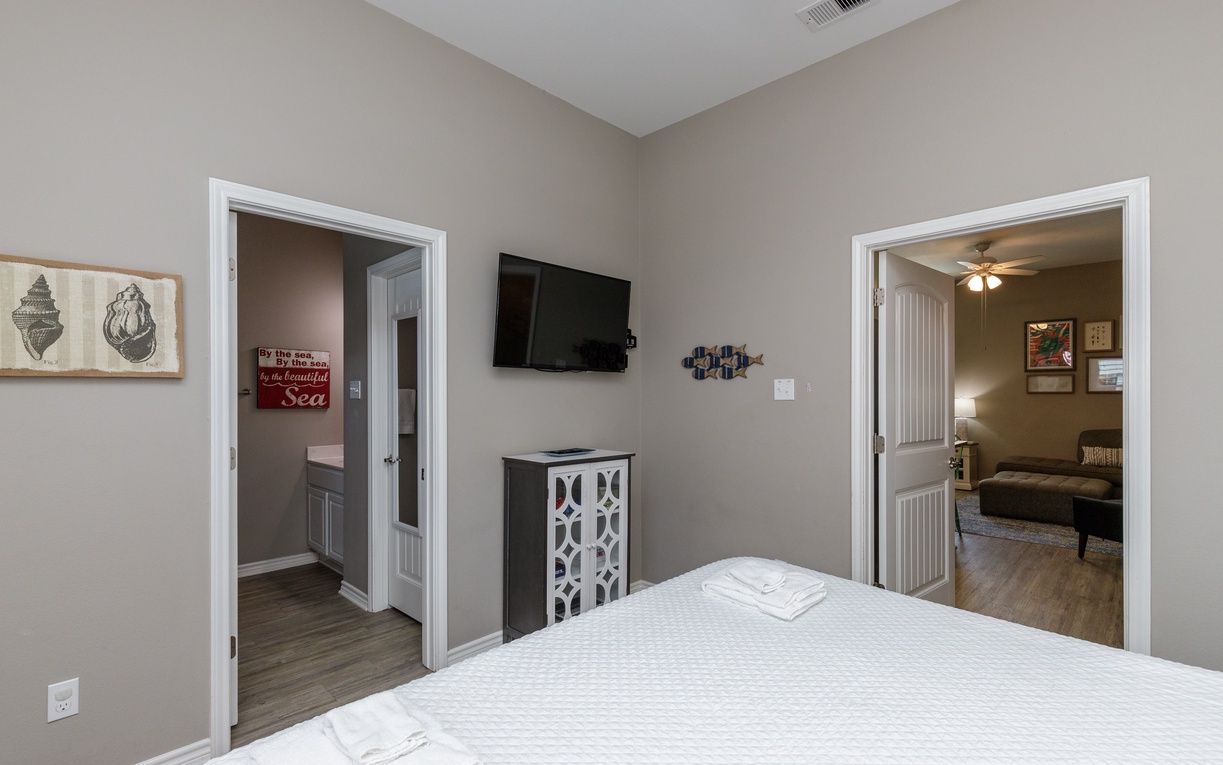 Relax in your comfortable bedroom featuring a plush bed, mounted TV, and charming coastal décor that creates the perfect retreat.
